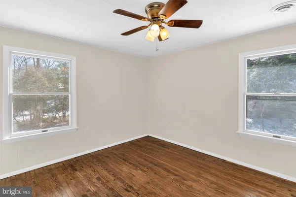 a view of empty room with wooden floor and fan