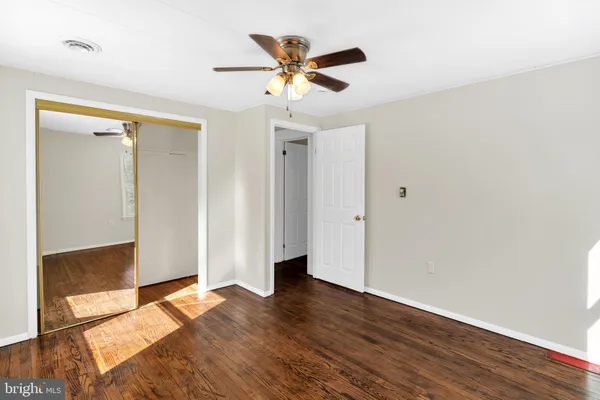 an empty room with wooden floor and a ceiling fan