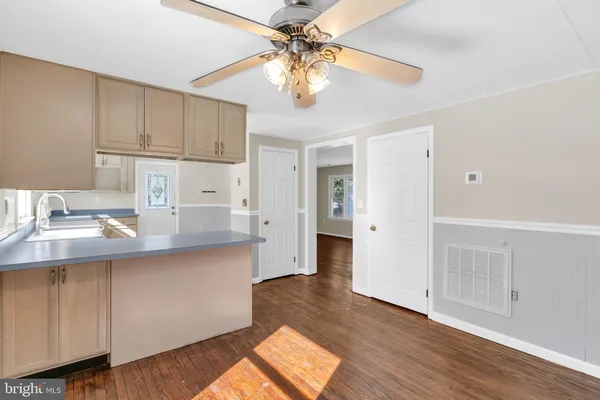 a kitchen with stainless steel appliances granite countertop a sink a stove and white cabinets with wooden floor
