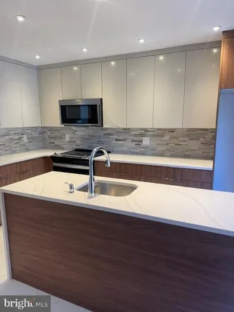 a kitchen with kitchen island granite countertop a sink and a stove