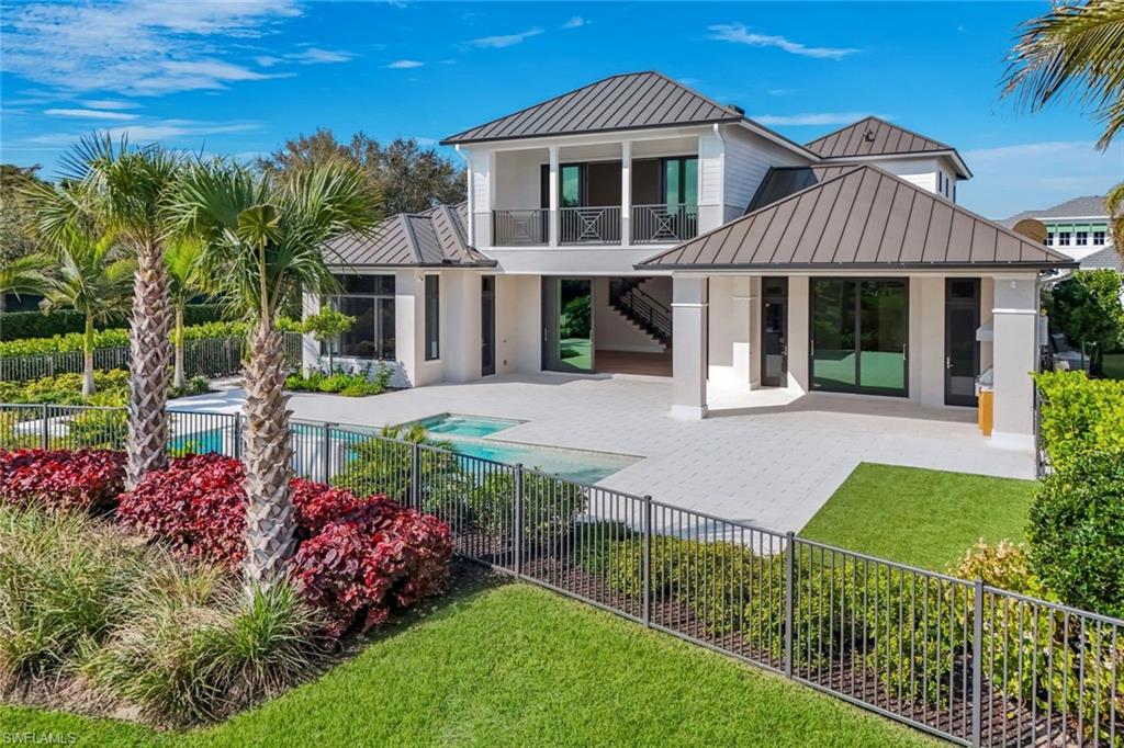 16728 Enclave Circle Naples, FL 34110 - Photo 1 of 49 Rear view of property with a standing seam roof, a patio, a balcony, and a fenced backyard
