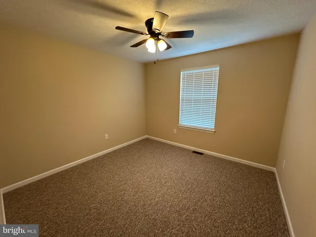 an empty room with a window and a fan