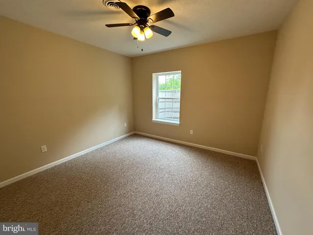 an empty room with a window and a fan