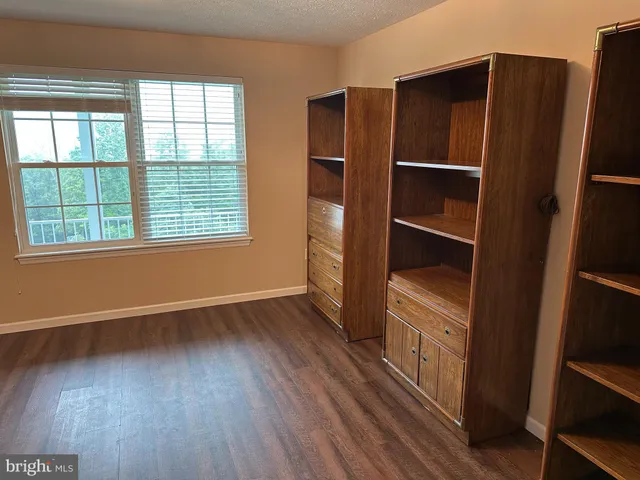 an empty room with wooden floor closet and windows