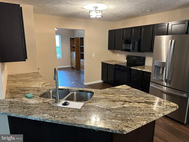 a kitchen with kitchen island granite countertop a stove refrigerator and microwave