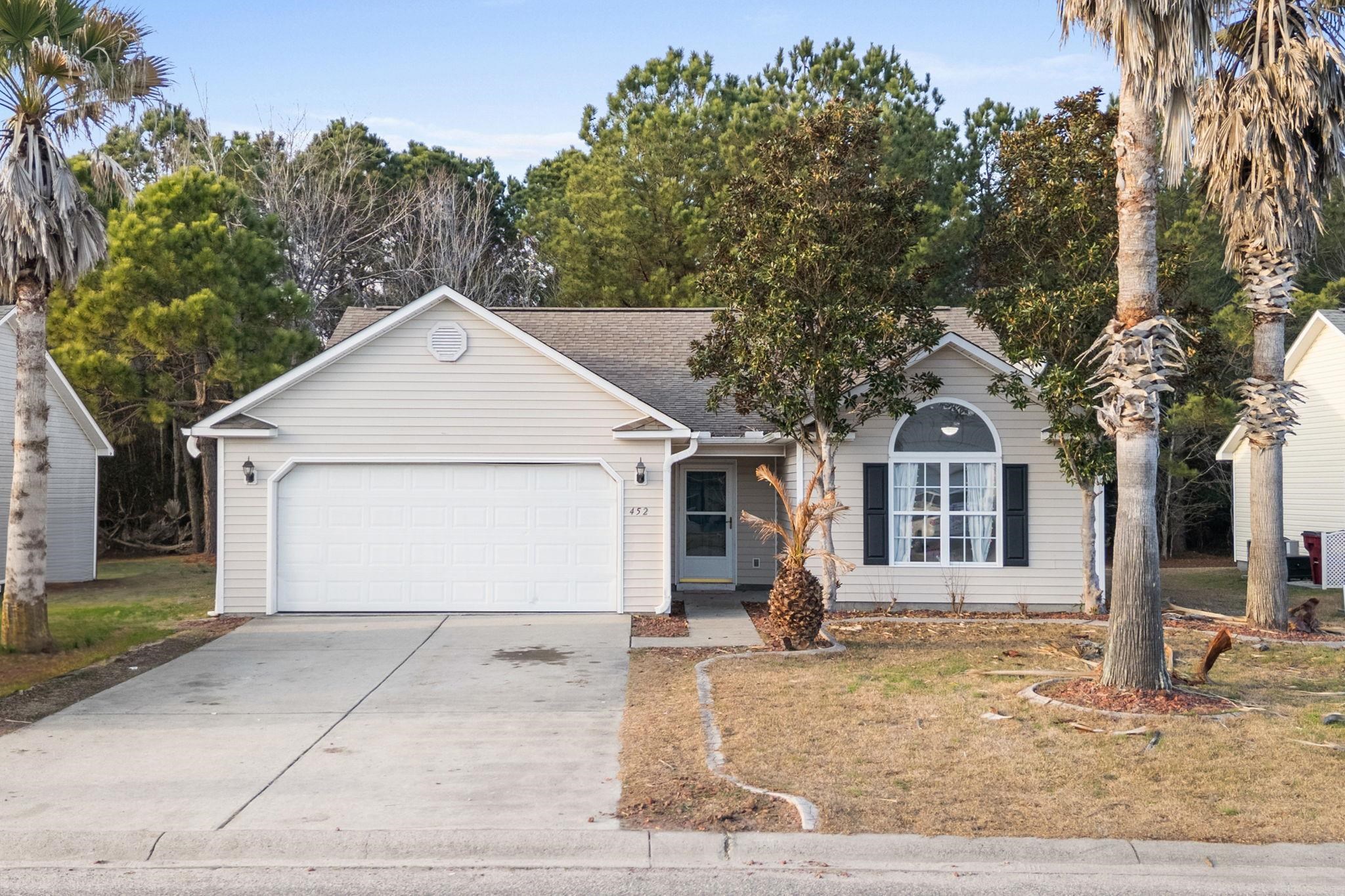 Ranch-style home featuring roof with shingles, concrete driveway, a garage, and a front lawn