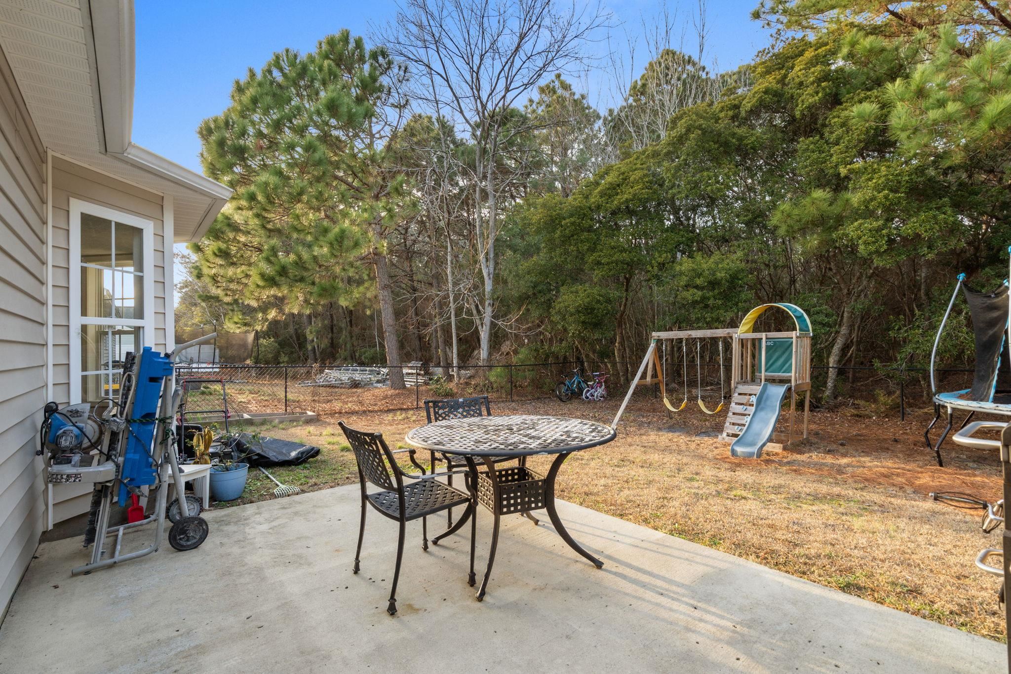 452 West Perry Road Myrtle Beach, SC 29579 - Photo 11 of 26 Fenced backyard with a playground, a trampoline, a patio area, outdoor dining area, and view of wooded area