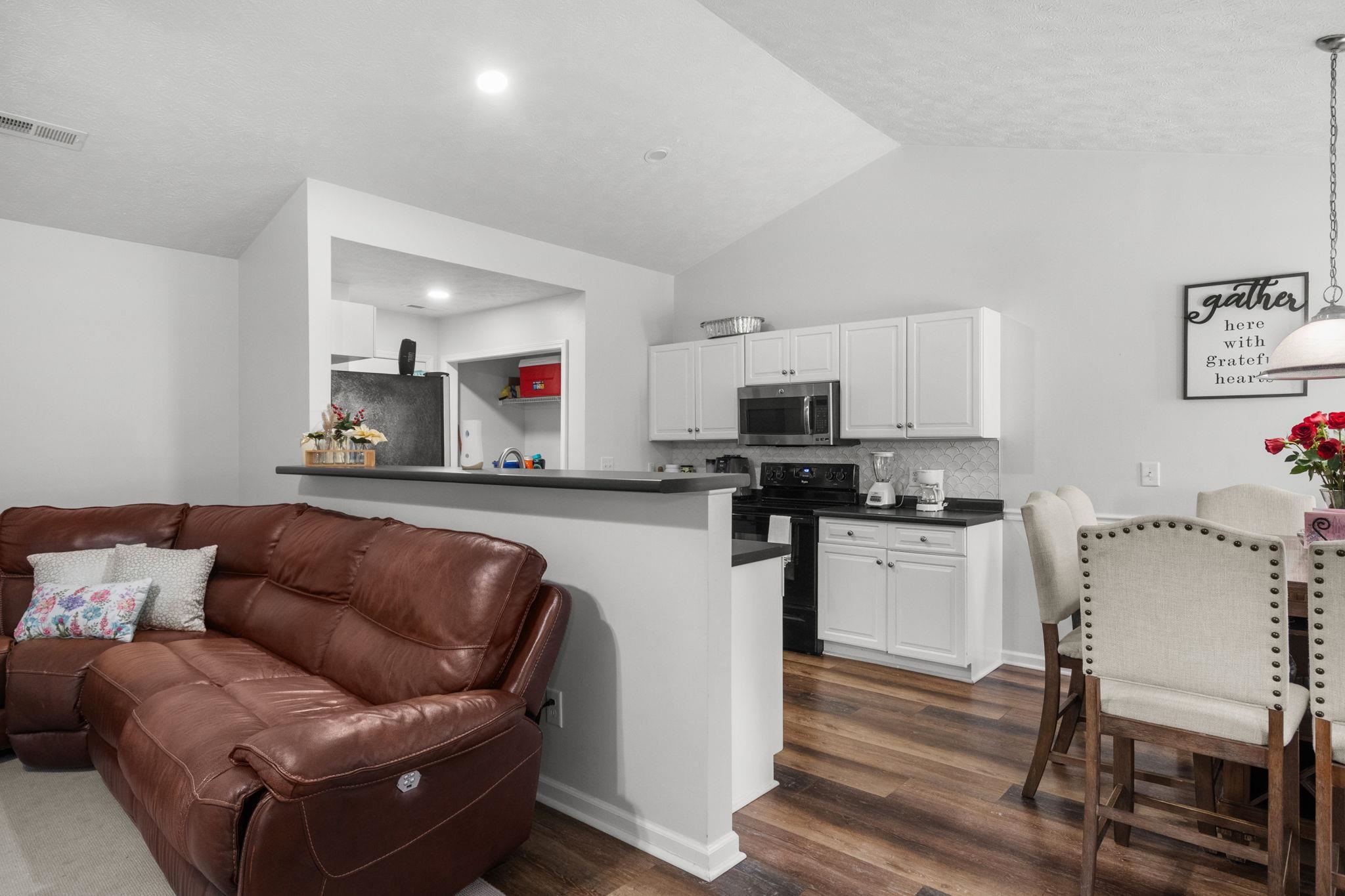 452 West Perry Road Myrtle Beach, SC 29579 - Photo 7 of 26 Kitchen featuring dark countertops, decorative backsplash, appliances with stainless steel finishes, white cabinetry, and lofted ceiling