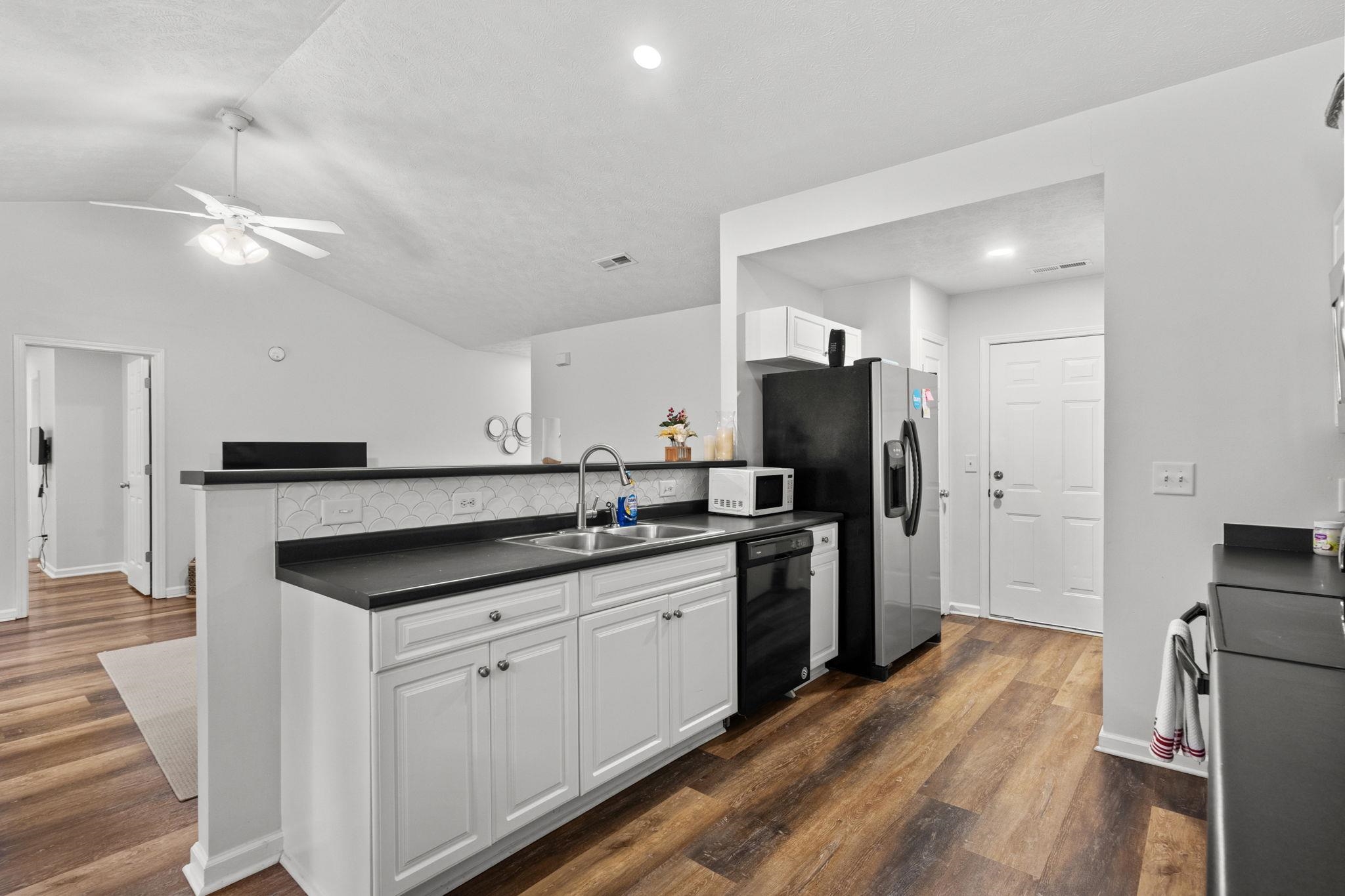 452 West Perry Road Myrtle Beach, SC 29579 - Photo 8 of 26 Kitchen with white cabinetry, lofted ceiling, dark countertops, stainless steel appliances, and dark wood-type flooring