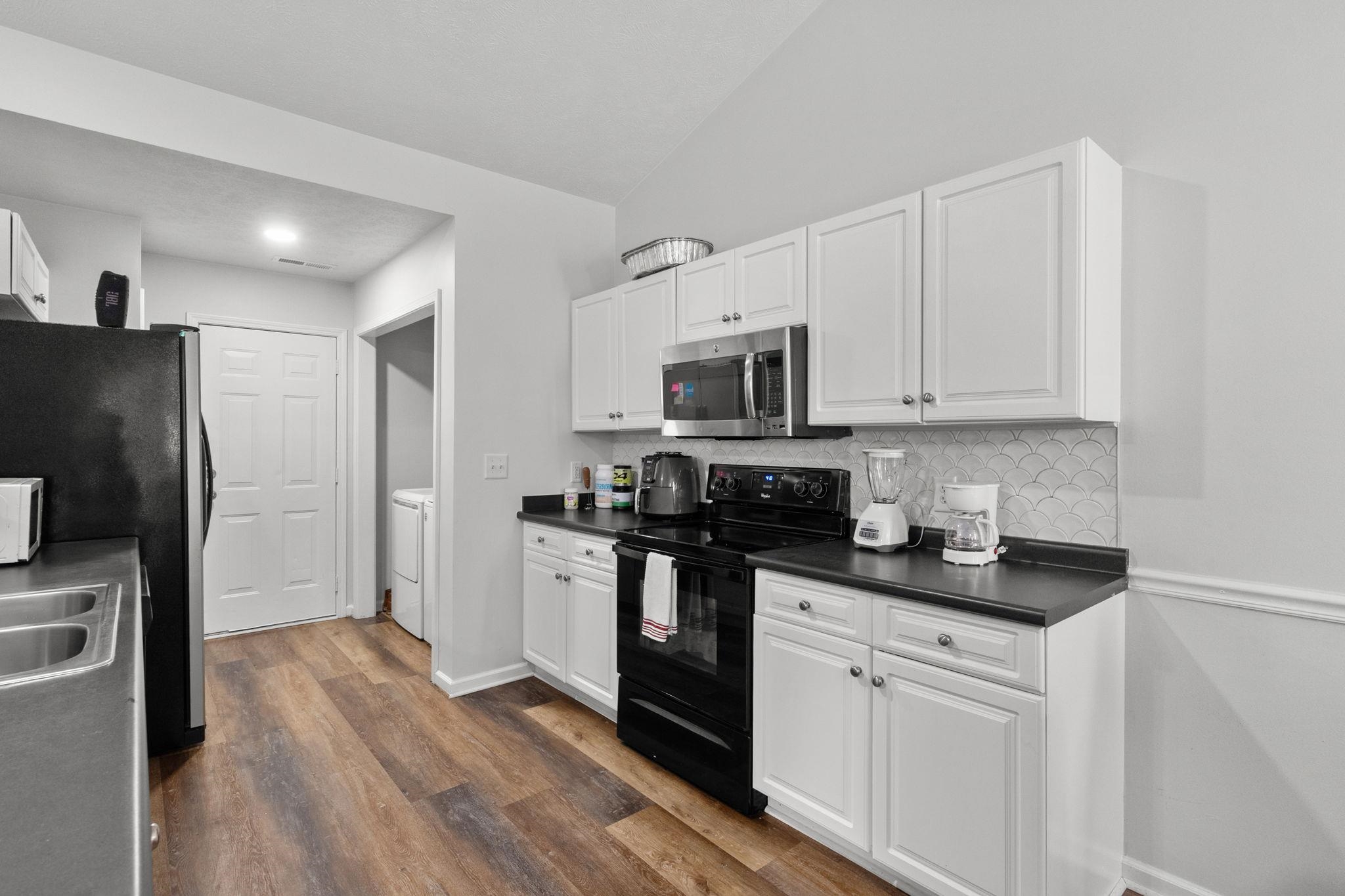 452 West Perry Road Myrtle Beach, SC 29579 - Photo 9 of 26 Kitchen featuring stainless steel appliances, dark countertops, white cabinetry, vaulted ceiling, and backsplash