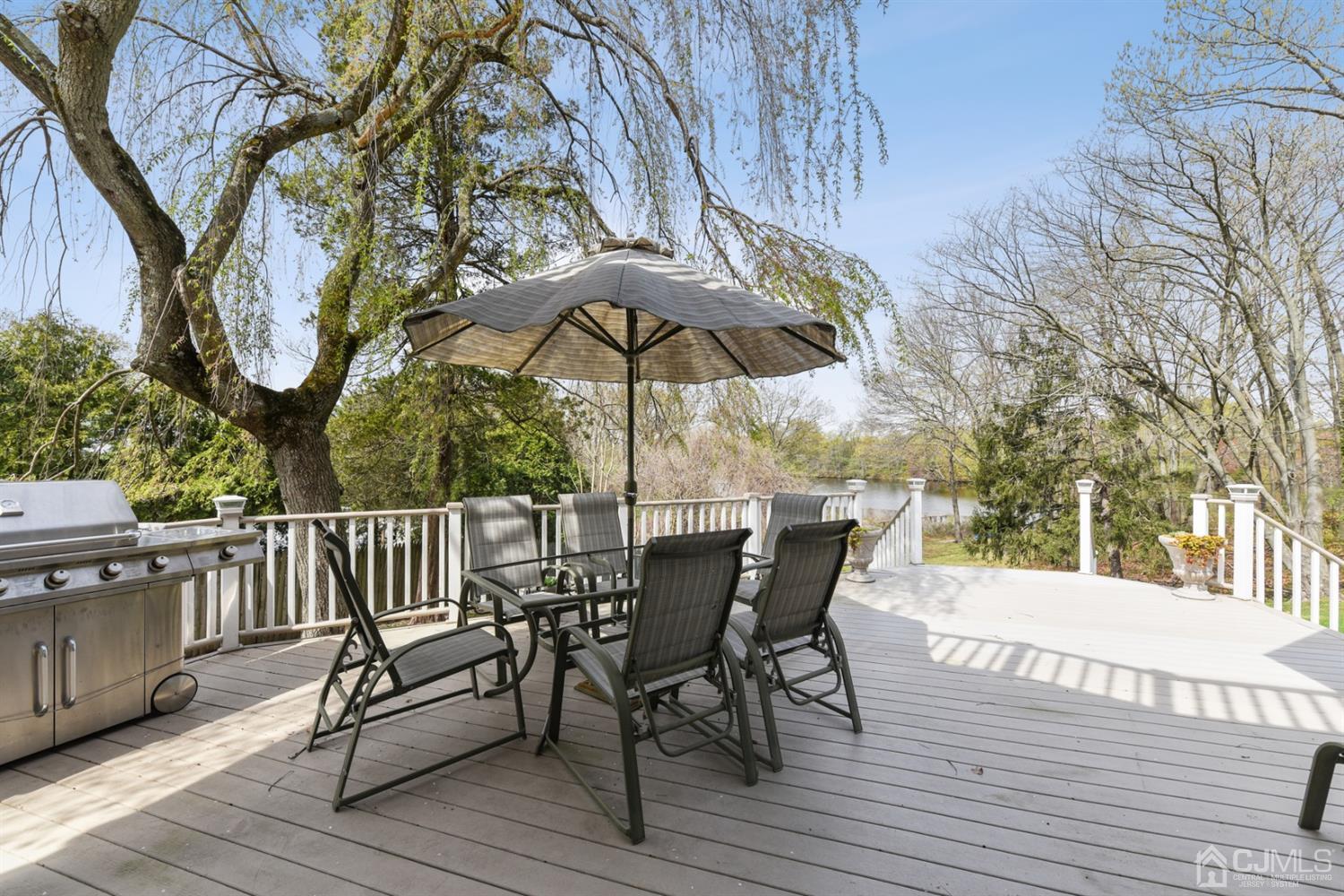 27 Agate Road East Brunswick, NJ 08816 - Photo 26 of 31 a view of a roof deck with table and chairs under an umbrella with wooden floor and fence