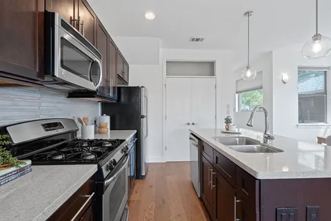 a kitchen with stainless steel appliances granite countertop a sink stove and refrigerator