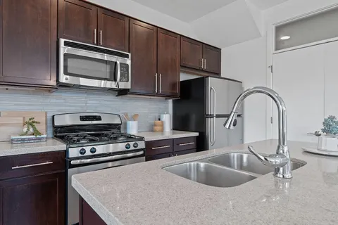 a kitchen with granite countertop a sink and a stove top oven with wooden floor