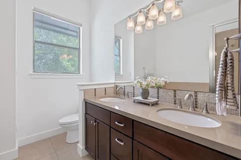 a bathroom with a granite countertop double vanity sink mirror and toilet