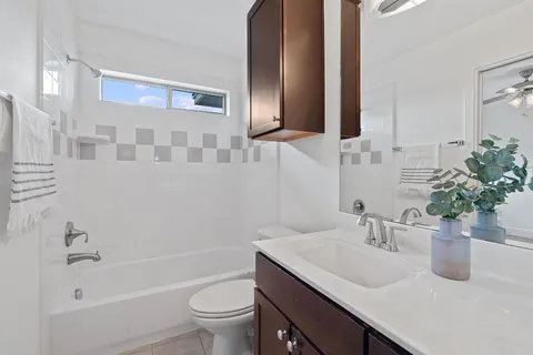 a bathroom with a granite countertop sink a toilet a mirror and shower