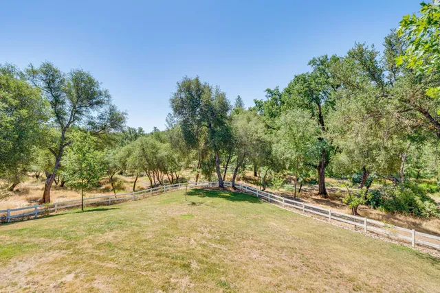 a view of a house with a big yard and large trees