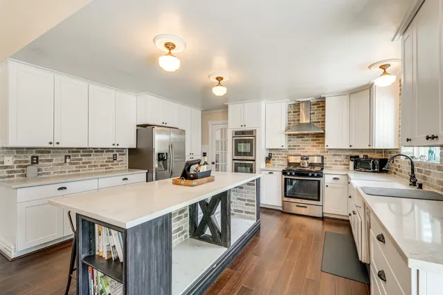 a kitchen with a stove a sink dishwasher a refrigerator and a stove with wooden floor