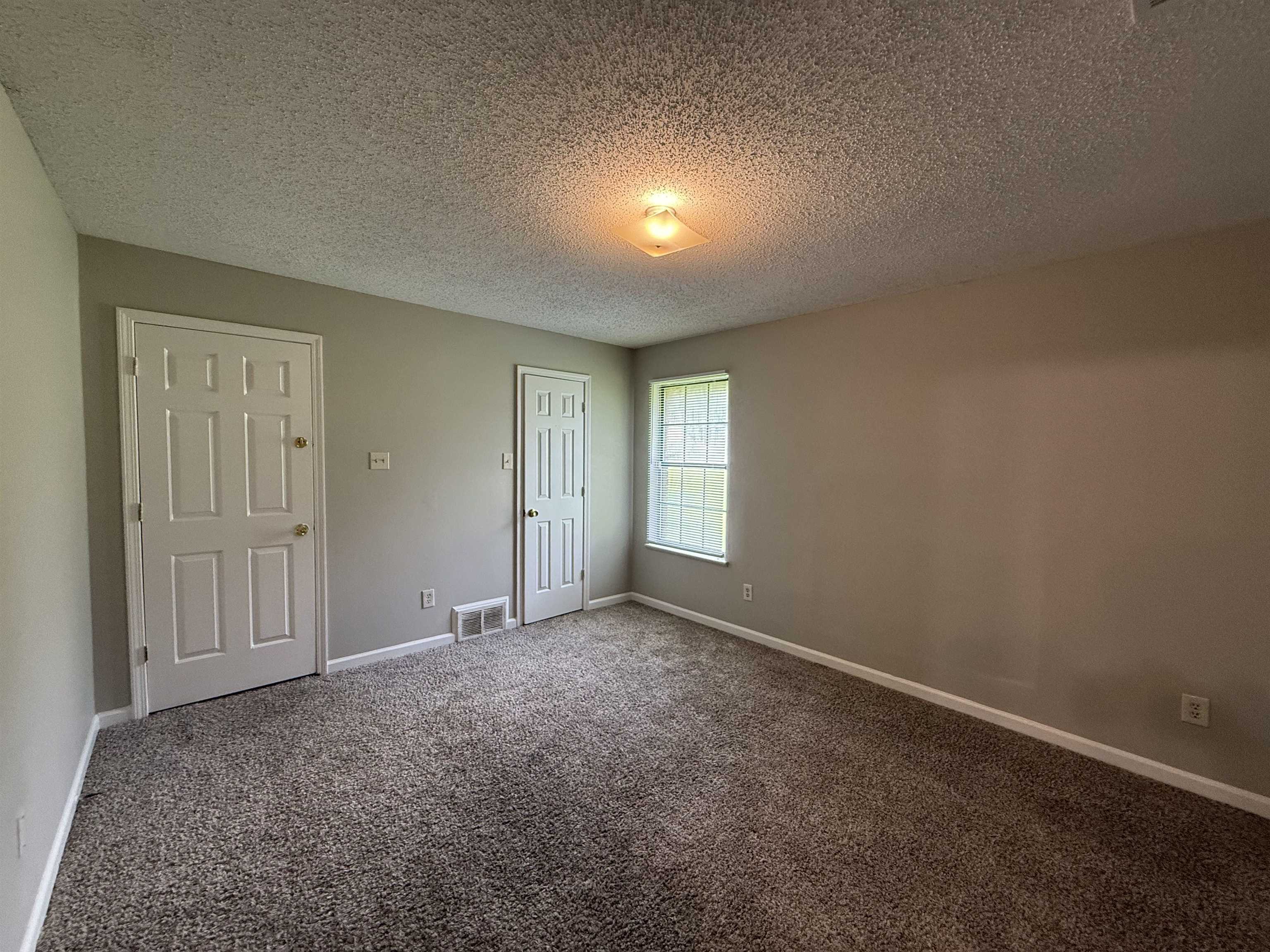 6420 Saginaw Road Memphis, TN 38134 - Photo 27 of 38 Neutral-toned room featuring a window with natural light, two panel doors, and a textured ceiling