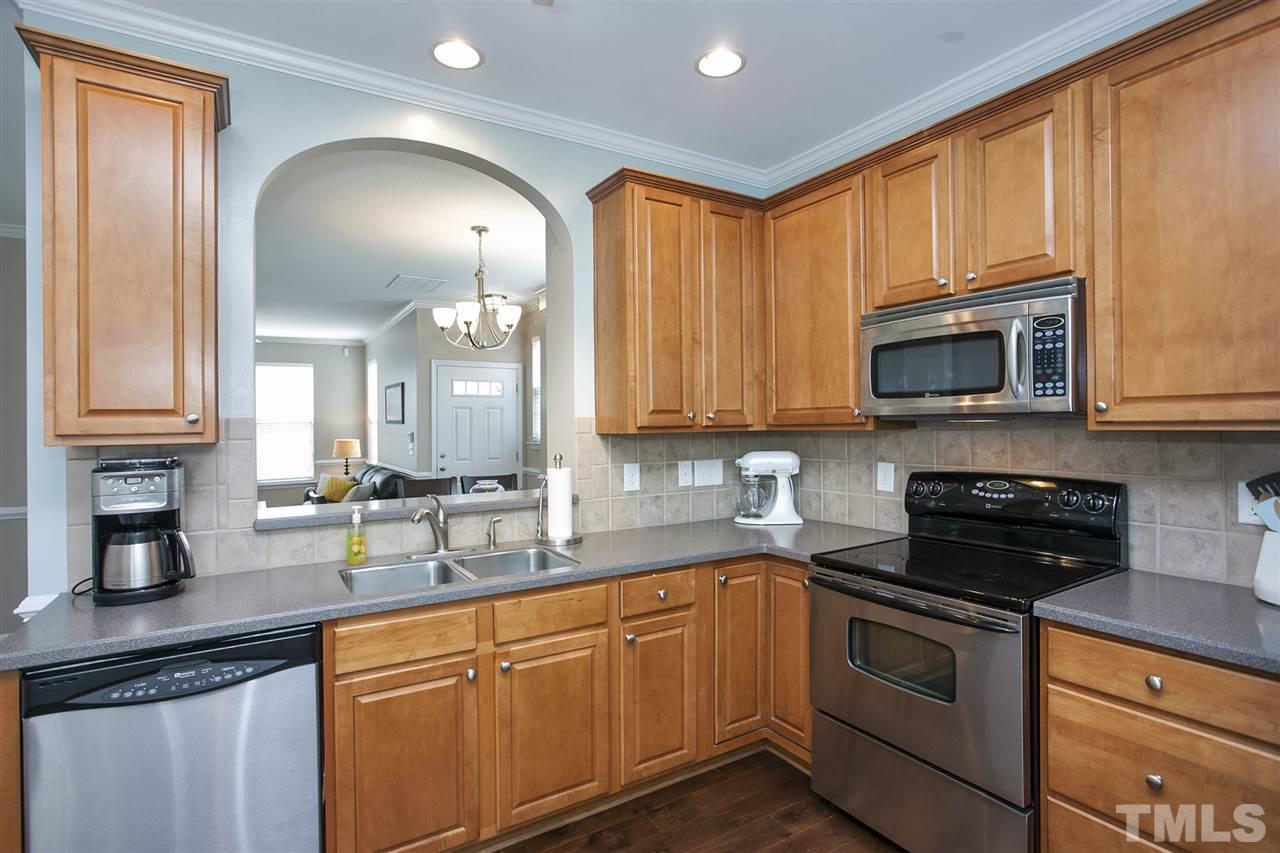 7725 Winners Edge Street Raleigh, NC 27617 - Photo 11 of 25 a kitchen with stainless steel appliances granite countertop a sink a stove a microwave oven with cabinets and wooden floor