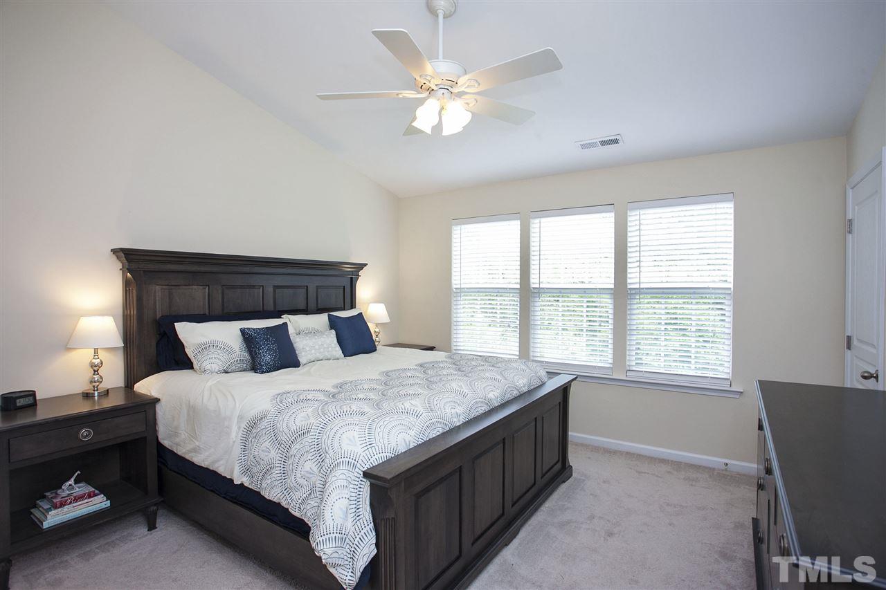 7725 Winners Edge Street Raleigh, NC 27617 - Photo 13 of 25 a bedroom with a bed and a large window with a chandelier