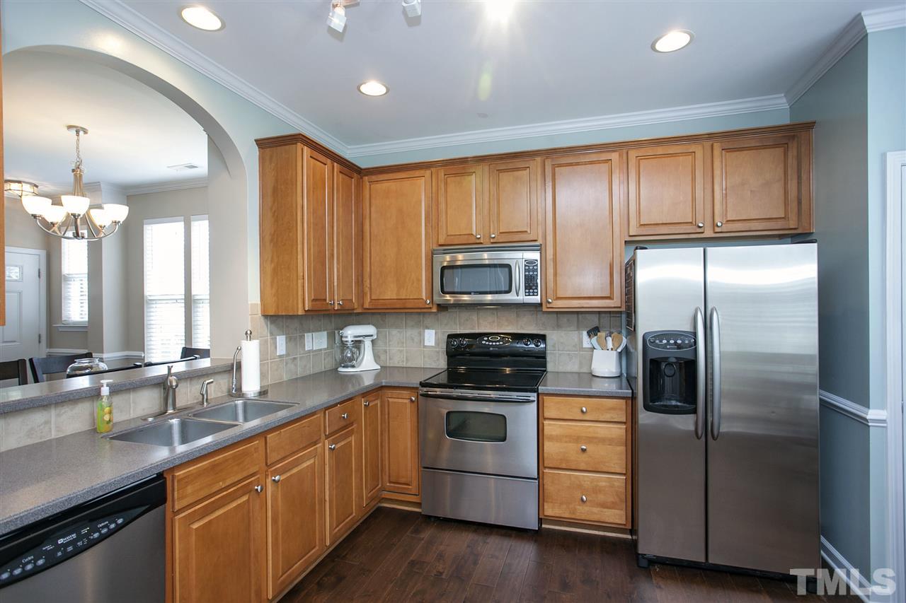 7725 Winners Edge Street Raleigh, NC 27617 - Photo 10 of 25 a kitchen with stainless steel appliances granite countertop a refrigerator a sink dishwasher a stove and white cabinets with wooden floor