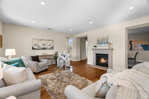 a kitchen with stainless steel appliances kitchen island granite countertop a stove a sink a refrigerator and white cabinets with wooden floor