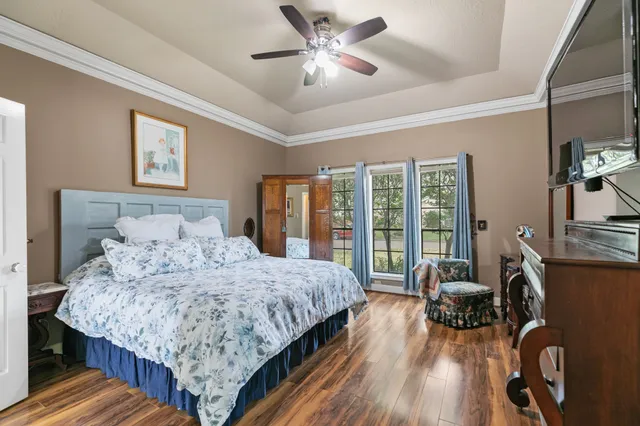 a bedroom with a bed a couch and dresser with wooden floor