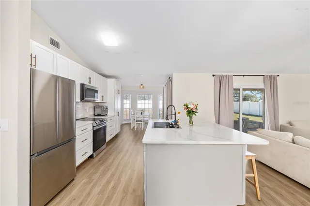 a kitchen with stainless steel appliances a refrigerator a sink a stove a dining table and chairs