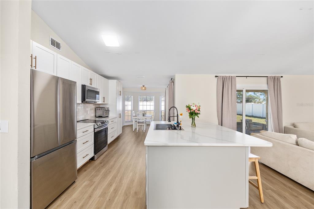 14 Bahia Trace Loop Ocala, FL 34472 - Photo 23 of 46 a kitchen with stainless steel appliances a refrigerator a sink a stove a dining table and chairs