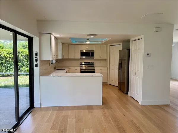 a view of kitchen with stainless steel appliances granite countertop a stove a sink and a refrigerator