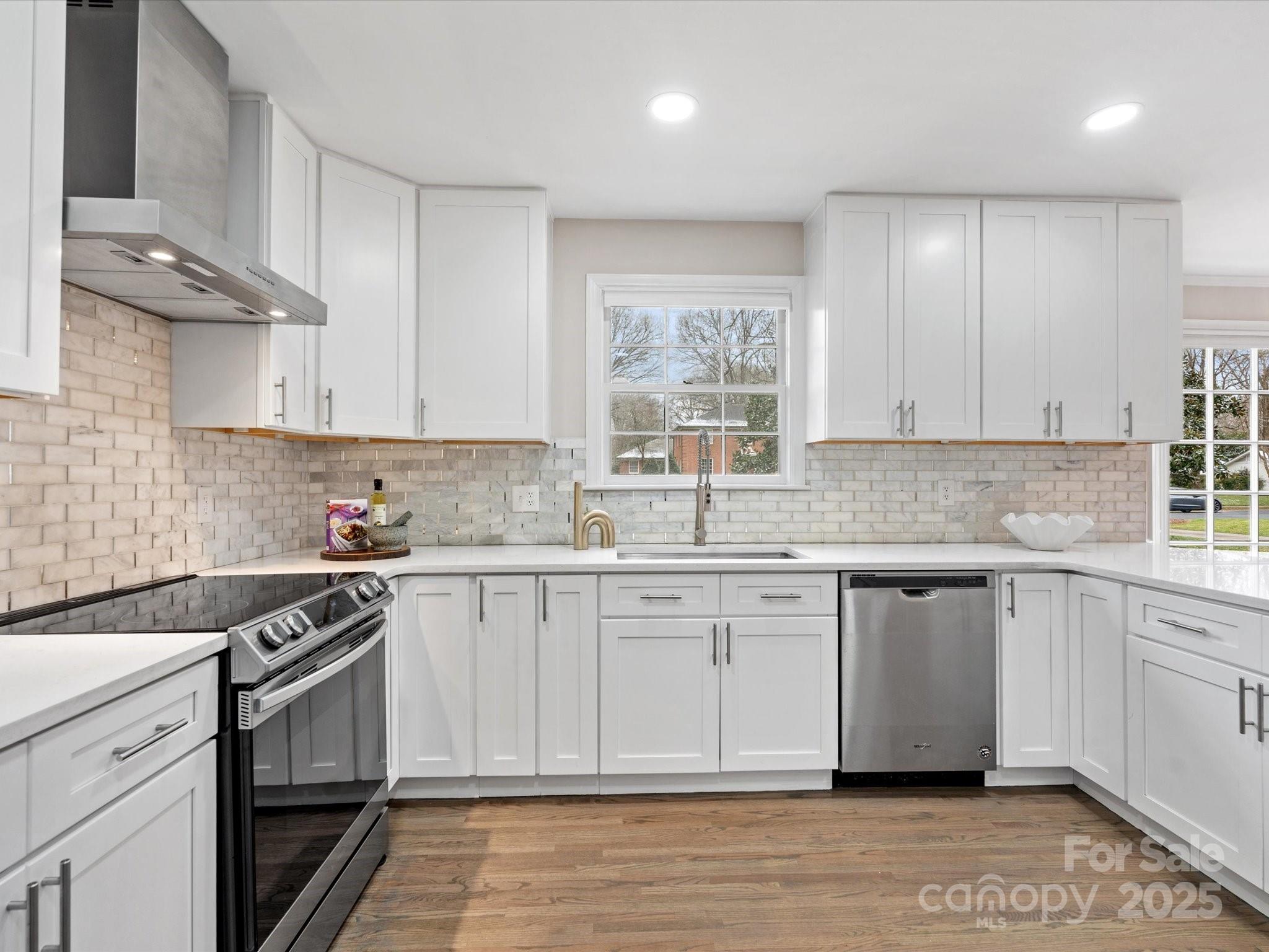 a kitchen with stainless steel appliances granite countertop a stove and white cabinets