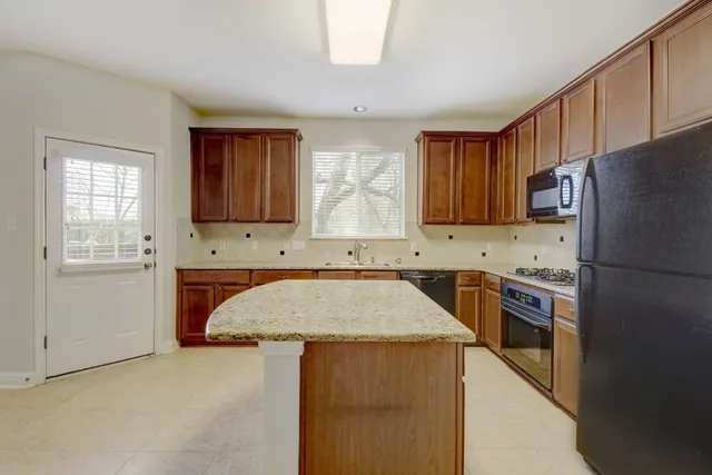 a kitchen with stainless steel appliances granite countertop a refrigerator sink and stove