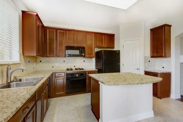 a kitchen with stainless steel appliances granite countertop a sink stove microwave and refrigerator