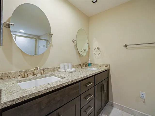 a bathroom with a granite countertop double vanity sink and a mirror