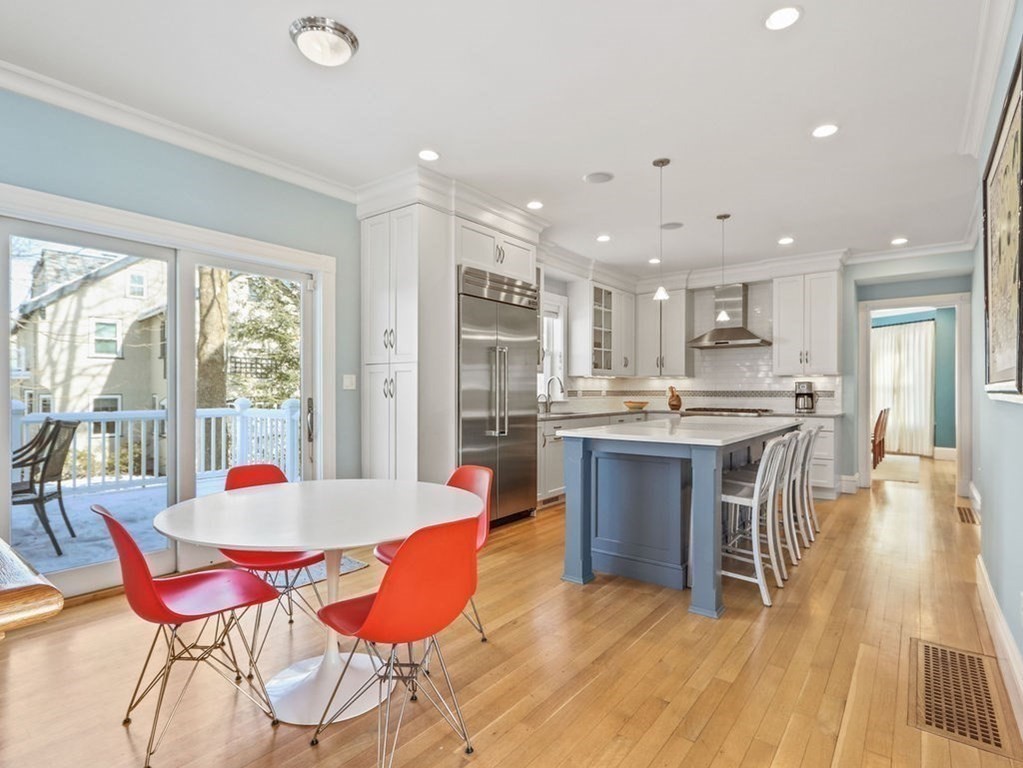 53 Marshall Street Newton, MA 02459 - Photo 5 of 42 a open dining room with stainless steel appliances kitchen island granite countertop a refrigerator a stove a sink with a dining table and chairs with wooden floor