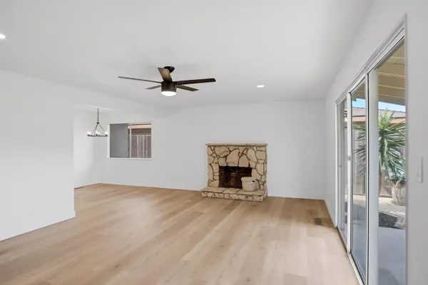 a view of an empty room with a window and a kitchen