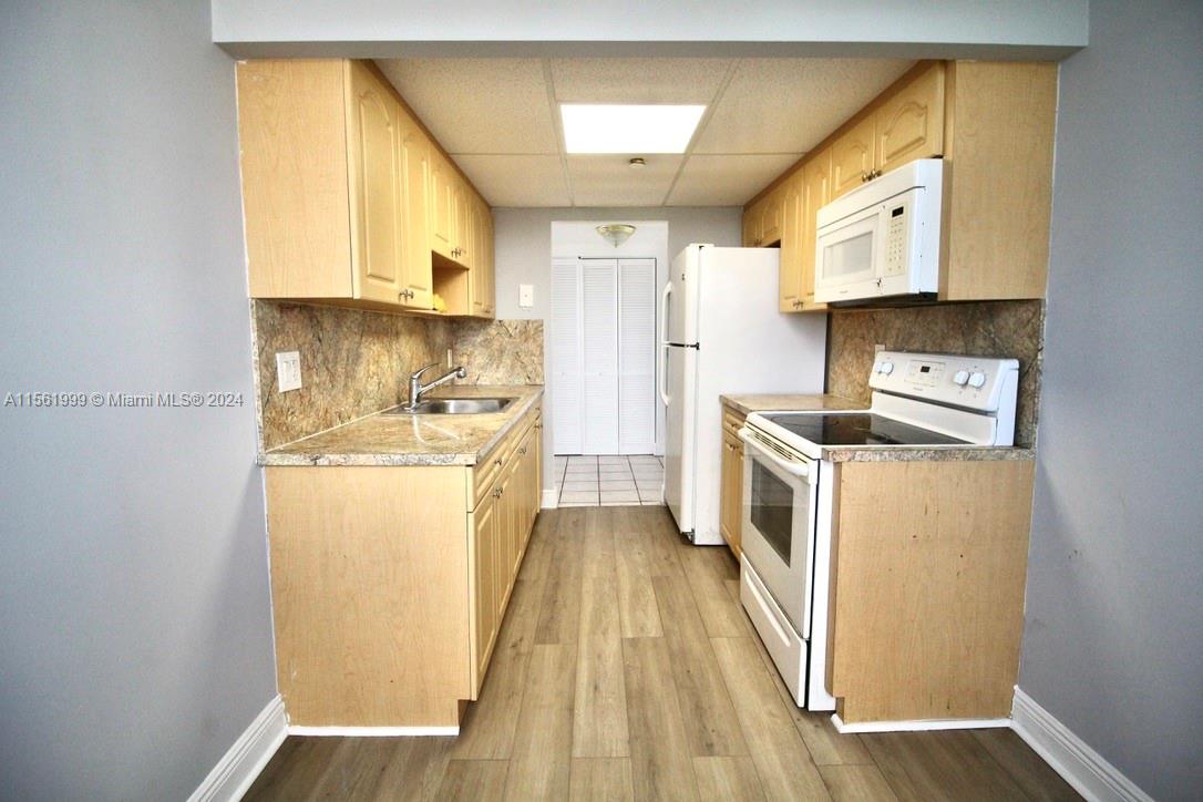 a kitchen with a refrigerator a stove top oven a sink and dishwasher with wooden floor