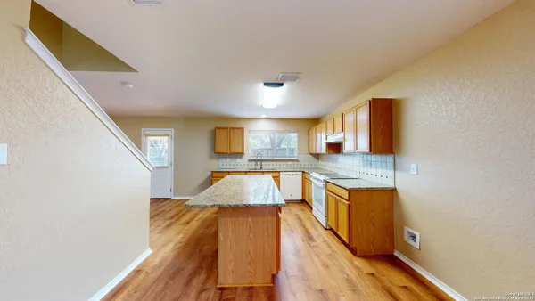 a living room with stainless steel appliances kitchen island granite countertop furniture and a wooden floor
