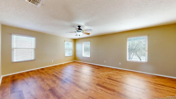 a view of an empty room with window and wooden floor