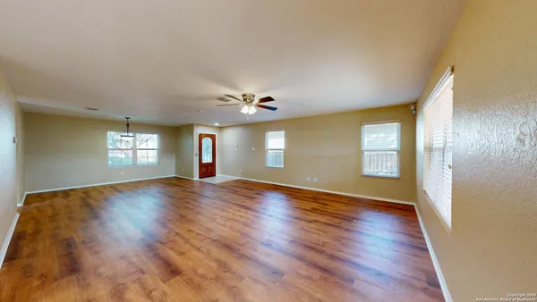 a view of empty room with wooden floor and fan