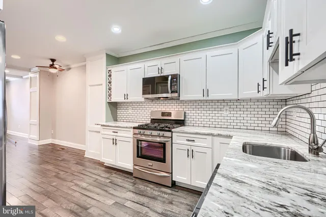 a kitchen with granite countertop a sink a stove and refrigerator