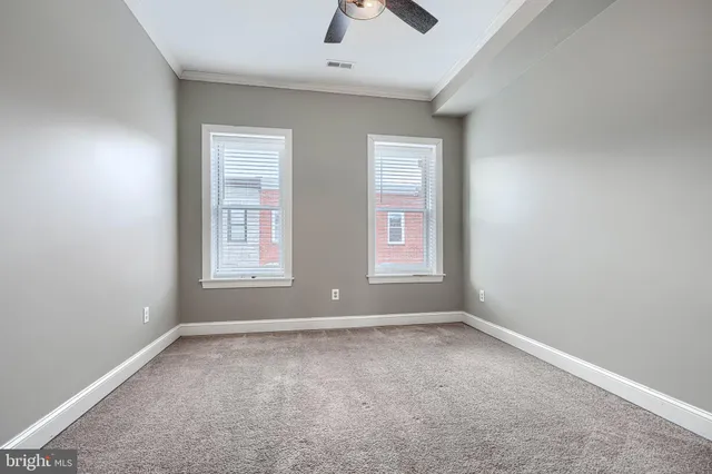 an empty room with windows and chandelier fan