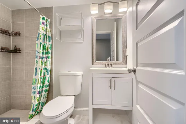 a bathroom with a sink a toilet a mirror and shower