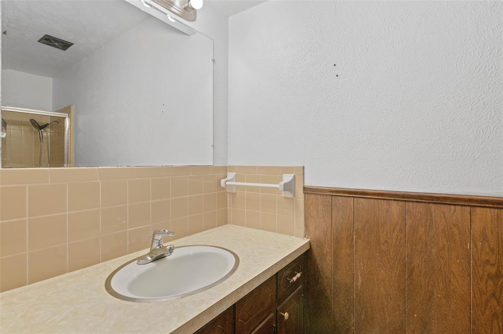 301 East 6th Street Krum, TX 76249 - Photo 12 of 29 Primary bathroom with tile backsplash and beautiful custom wood cabinetry.