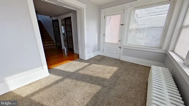 a view of an empty room with window and wooden floor