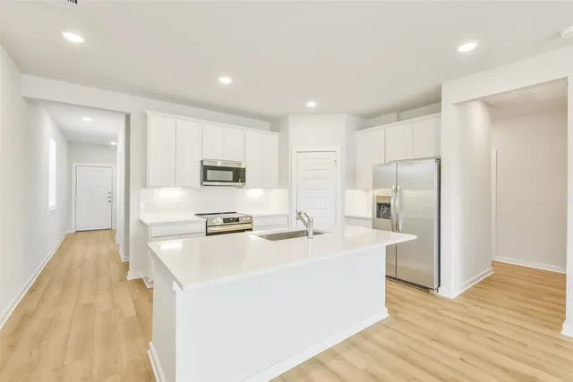 a kitchen with stainless steel appliances a refrigerator a stove and white wooden cabinets