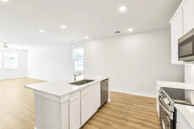 a kitchen with stainless steel appliances granite countertop a sink and a stove with wooden floor