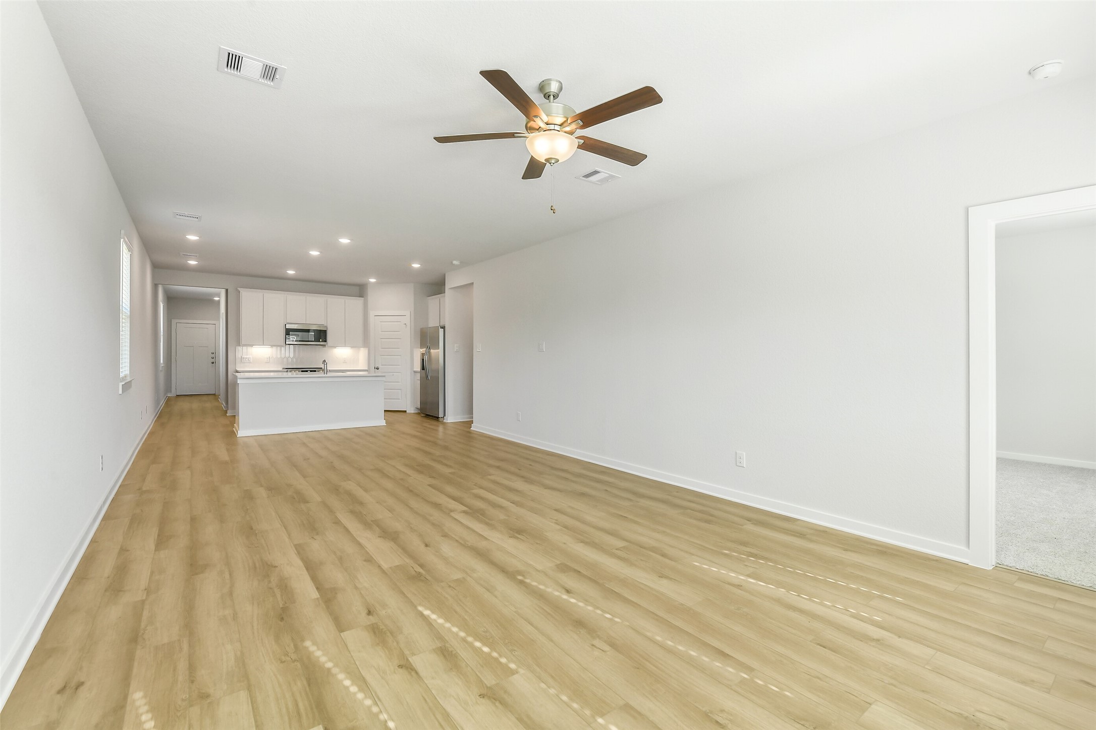 25980 Liberation Road Cleveland, TX 77328 - Photo 7 of 42 a view of a livingroom with a kitchen island wooden floor and a ceiling fan