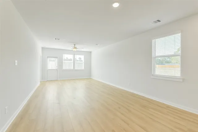 an empty room with wooden floor and windows