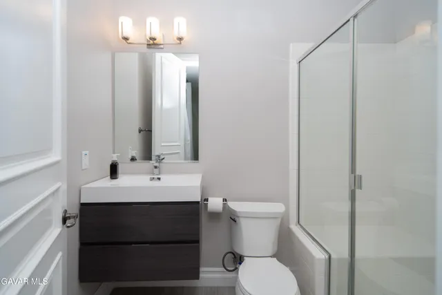 a bathroom with a granite countertop sink toilet and mirror